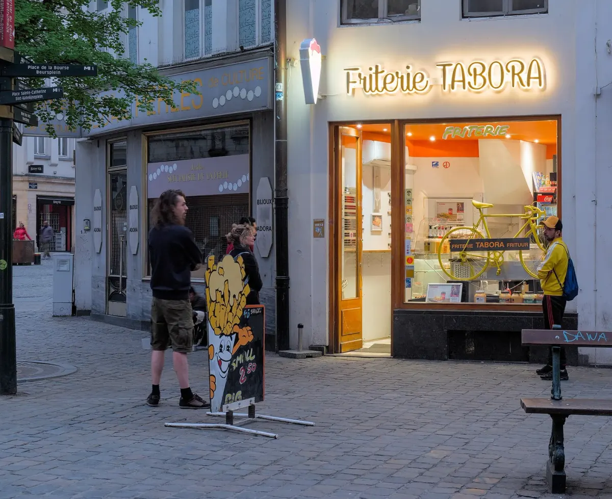 Comptoir d'une friterie en Belgique en soirée, avec des clients qui attendent leur commande